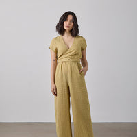 Woman wearing a yellow checkered jumpsuit against a plain background